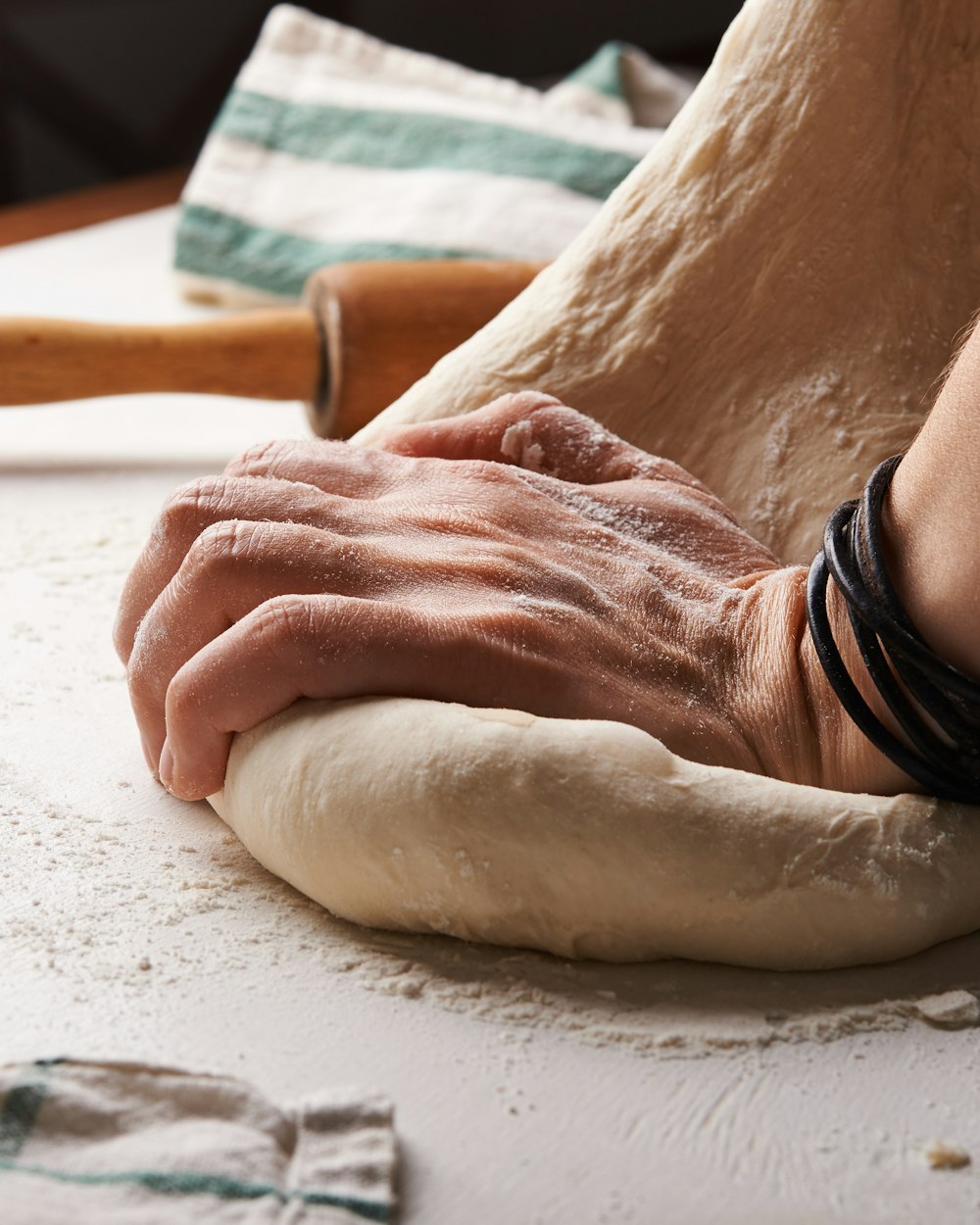 Les mains du boulanger pétrissant un pâton sur un plan de travail fariné