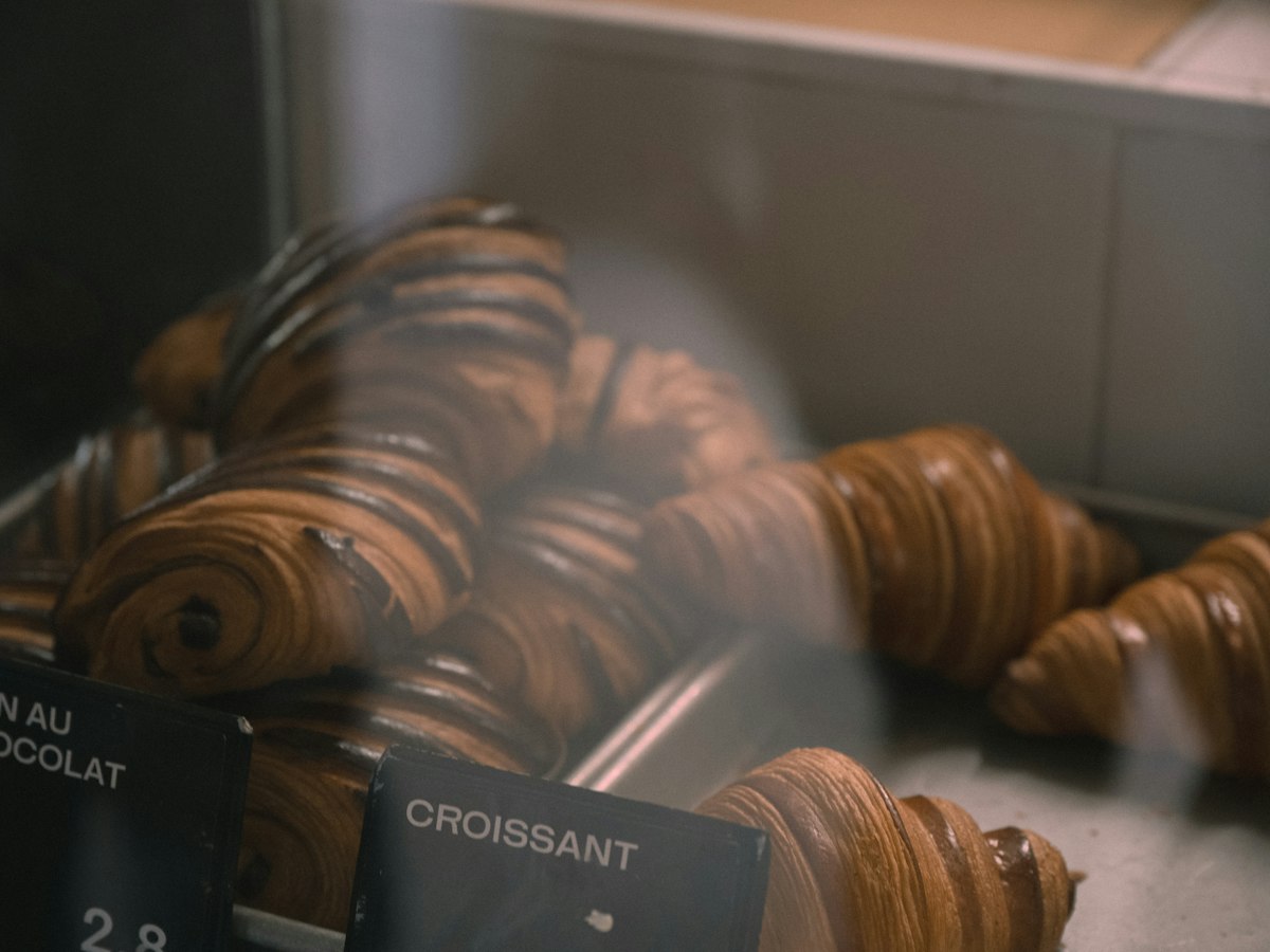 Croissants et pains au chocolat alignés dans la vitrine de la boulangerie